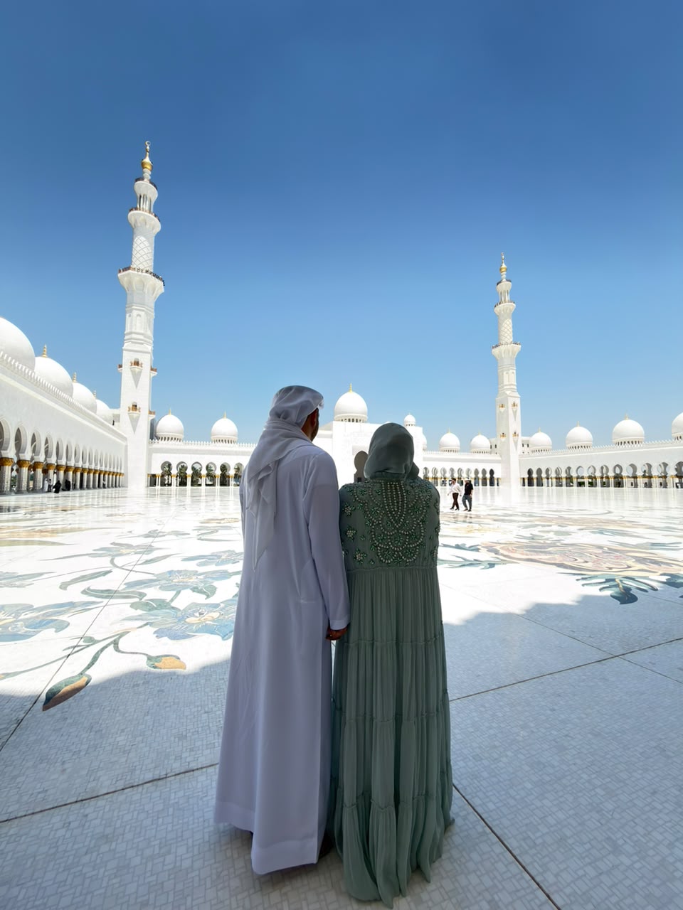 A couple standing together in a sunlit mosque courtyard
